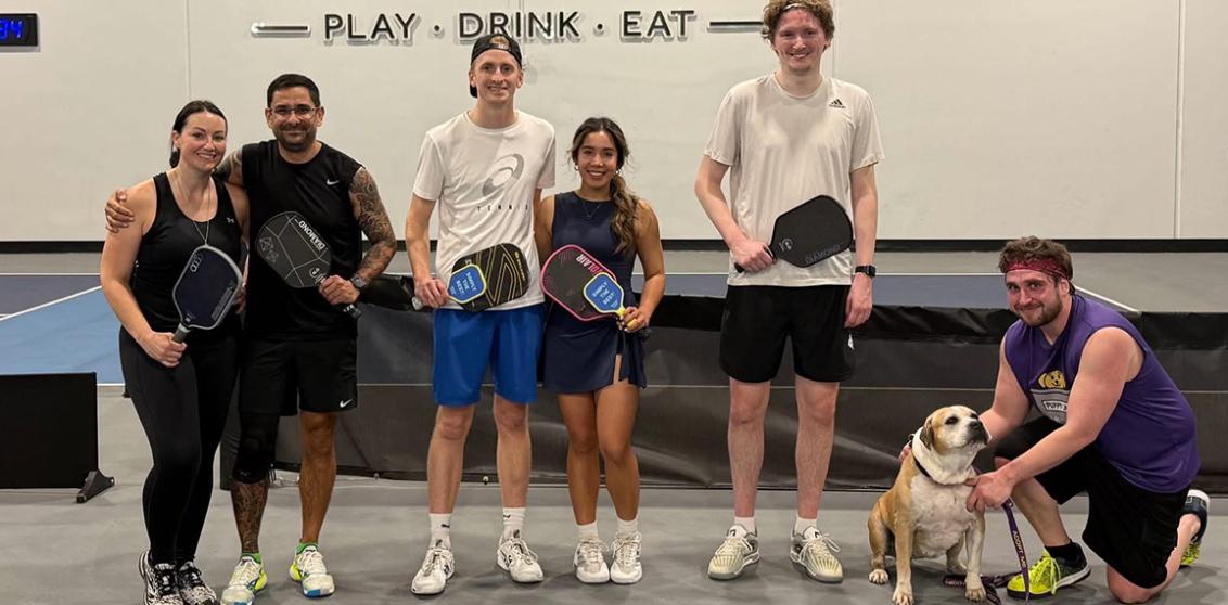 A group of people playing table tennis at a doggy day out program