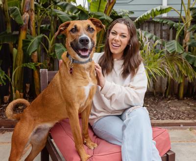 Smiling person sitting outside on a stone patio with a dog next to them
