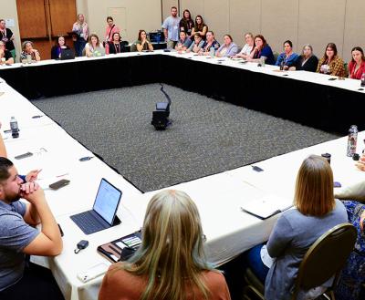 Best Friends National Conference attendees sitting around tables formed to make a large square