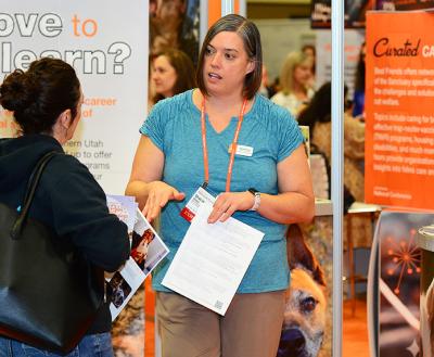 Person at an exhibitor booth speaking to a Best Friends National Conference