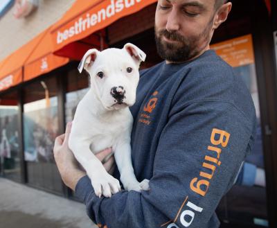 man holding white short-haired puppy outside Salt Lake City pet adoption center