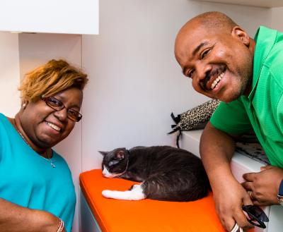 Two smiling people with a cat in SoHo pet adoption center