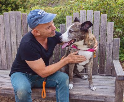 Person hugging a dog sitting on a bench next to them