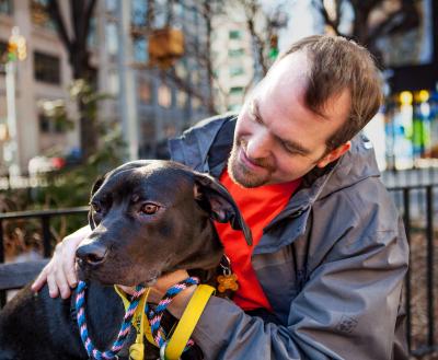 Person sitting with a dog outside in New York City