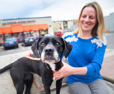 Smiling person sitting in front of Best Friends Pet Adoption Center in Salt Lake City with a dog
