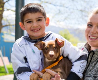 Two people smiling while sitting outside with an adopted dog