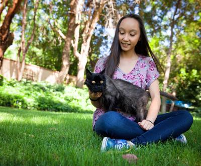 Smiling person sitting in the grass with a cat