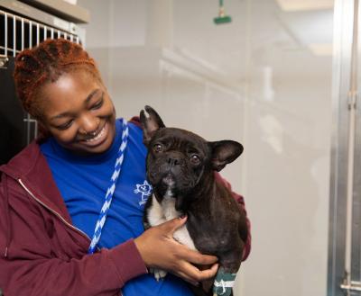 Shelter employee smiling at the dog in her arms.