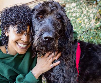 Smiling person hugging a fluffy, black dog