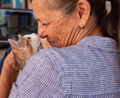 Smiling person snuggling face-to-face with a cat