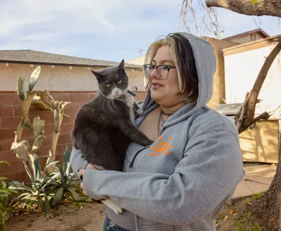 Person standing outside holding a cat in their arms
