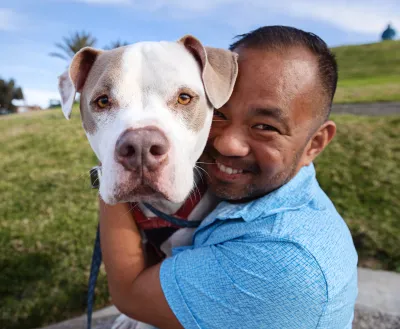 Smiling person hugging a dog outside
