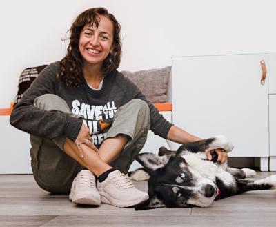 Person wearing BOBS® from Skechers® sitting on the floor petting a dog
