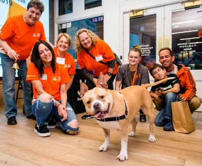 Group of smiling volunteers standing with a dog just adopted from Soho pet adoption center