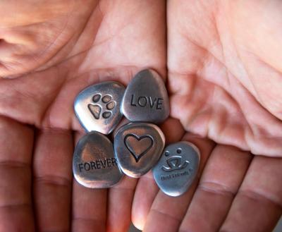 A pair of hands cupped and holding five memorial tokens