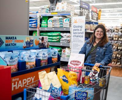 Smiling person pushing a cart full of pet supplies at a Walmart store