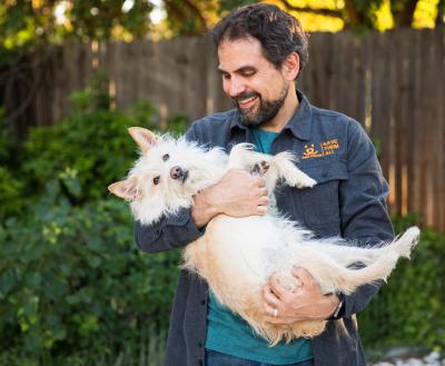 Person holding fluffy dog outside in a yard