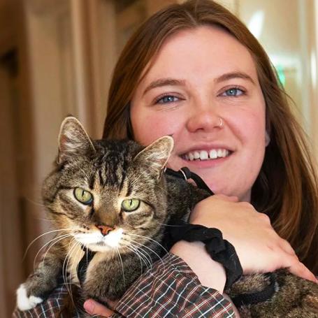 Smiling person holding a tabby and white cat