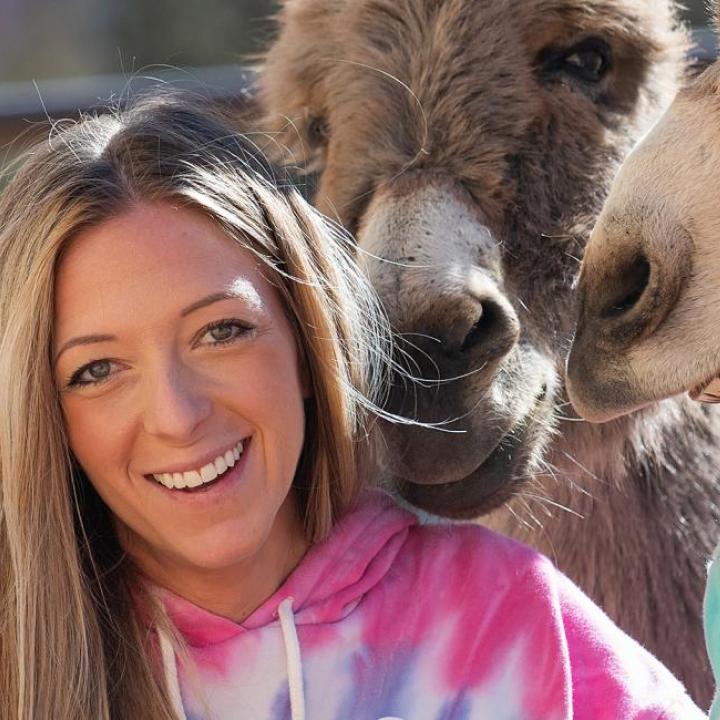 Person smiling while standing with a group of donkeys