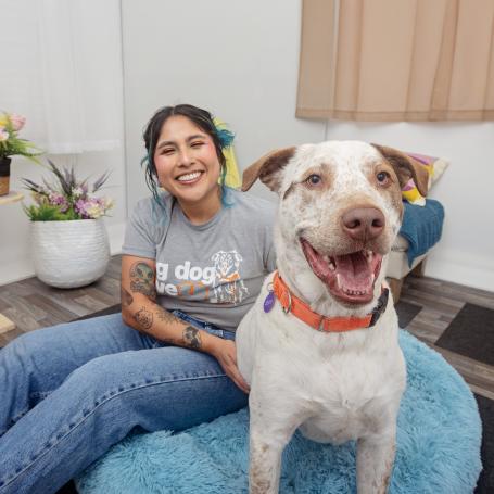 Smiling person sitting on the floor behind a dog