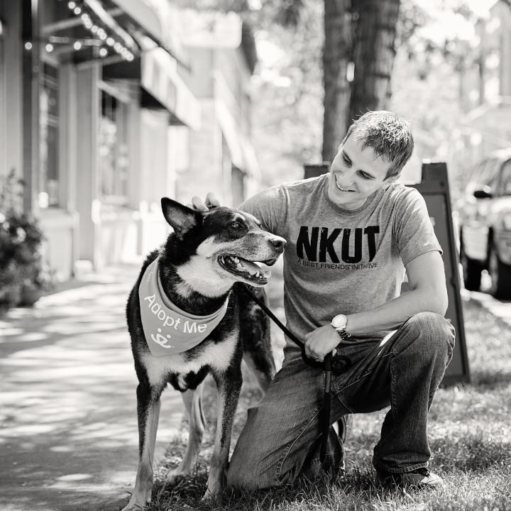 Man sitting with dog on sidewalk