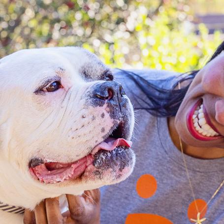 Smiling person sitting on a bench petting a dog