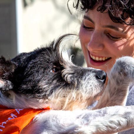 Smiling person holding a dog outside in a yard