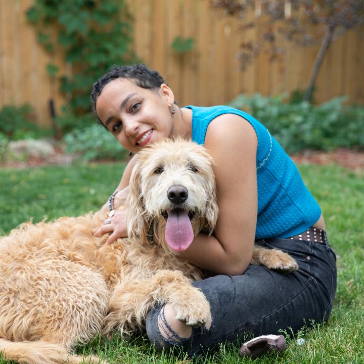 Woman sitting in yard with fluffy brown dog