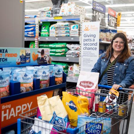 Smiling person pushing a cart full of pet supplies at a Walmart store