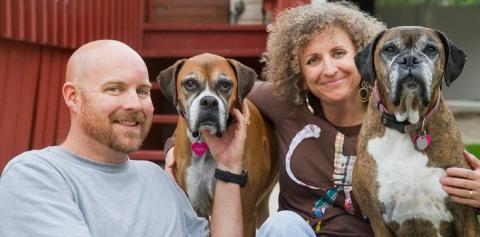 Man and woman in sitting on porch with two boxers
