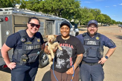 Two officers with a woman holding a small dog
