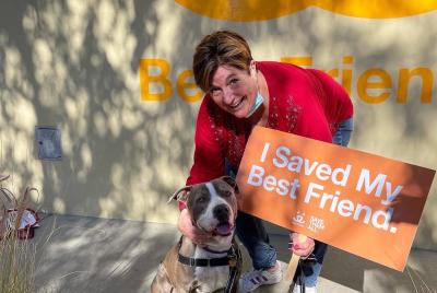 Picchu the dog's adopter with him holding a sign that says, 'I saved my best friend"