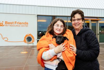Athena the puppy being held outside of the Best Friends Pet Resource Center in Northwest Arkansas by her new adopters