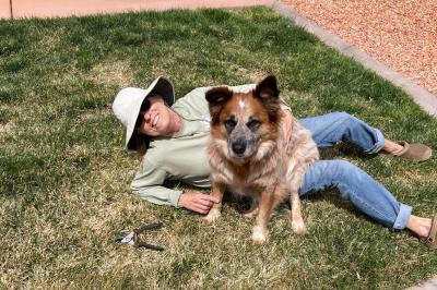 Racko the dog sitting next to a person lying in grass
