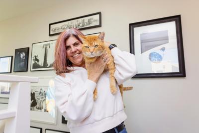 Steak the orange tabby cat lying on his adopter's shoulder