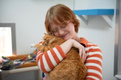 Smiling person holding a cat in their arms
