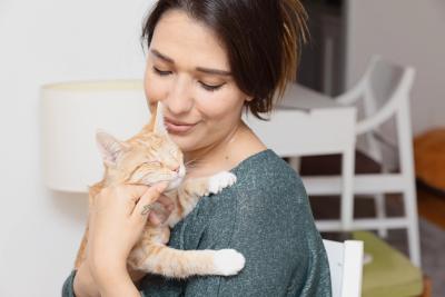Smiling person cradling an orange tabby cat in her arms