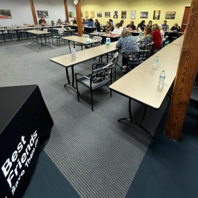 People attending a Best Friends Virginia Is for Animal Lovers Shelter Summit with a Best Friends logo on a table in foreground
