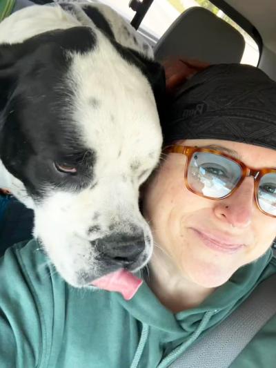 Georgia the dog with head over Jen's shoulder with her tongue out a bit