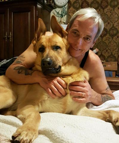 John lying down and hugging King George the dog