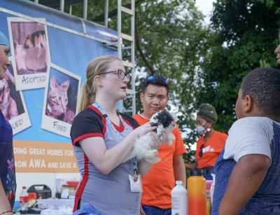 Person from AWA outside holding a puppy and talking to other people