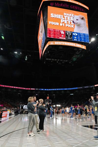People holding puppies on the court with Best Friends up on the jumbotron