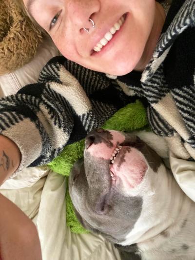 Selfie of smiling person lying down next to Bear the dog, also smiling