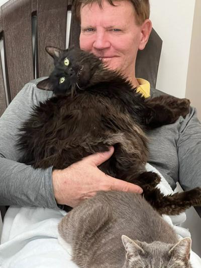 Volunteer Bill Coaker holding a longhair black cat