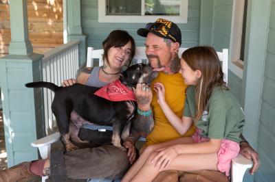 Family on a seat with a dog who is licking one of the people