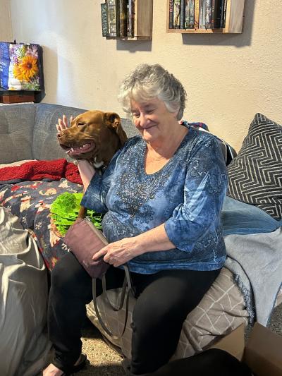 Bonnie the dog in a home sitting beside a person on a couch