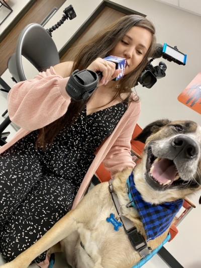 Ana talking into a microphone next to Brutus the dog who is smiling