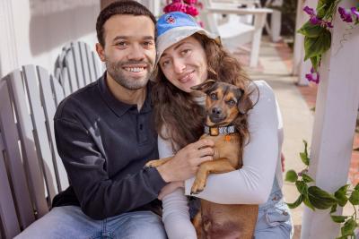 A couple sitting together holding a small brown dog