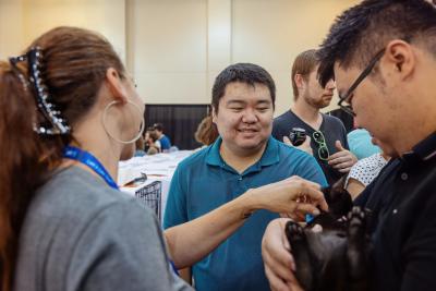 Person holding a black kitten while two other people look at and pet the kitten