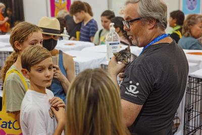 Person wearing a Best Friends T-shirt holding a kitten while some kids look